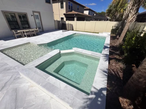 Close-up of spillover spa and geometric pool with sun shelf and water bubblers.