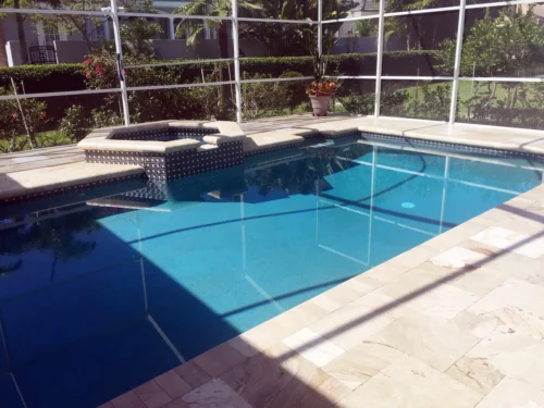 Custom built geometric pool with spillover spa inside screen enclosure.