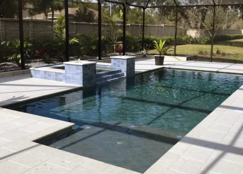 Custom built geometric pool with spillover spa & sun shelf inside screen enclosure.
