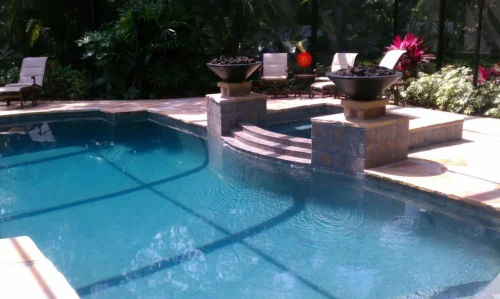Custom geometric pool with fire bowls and spillover spa