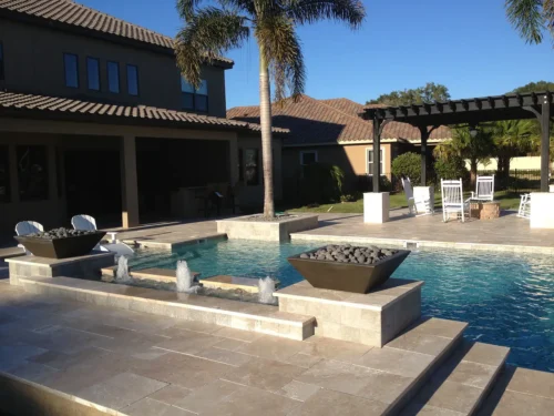 Custom geometric pool with sun shelf, water features, fire bowls, and fire pit under pergola