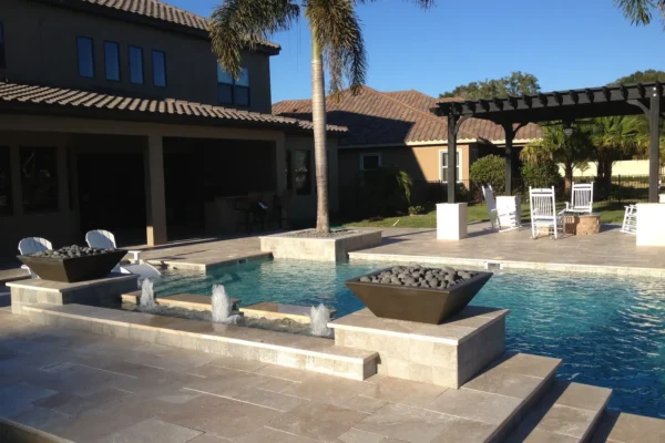 Custom geometric pool with sun shelf, water features, fire bowls, and fire pit under pergola