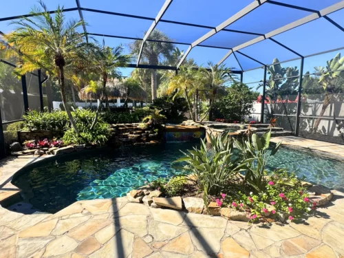 Freeform, lagoon style pool with spillover spa, waterfalls, and planters.