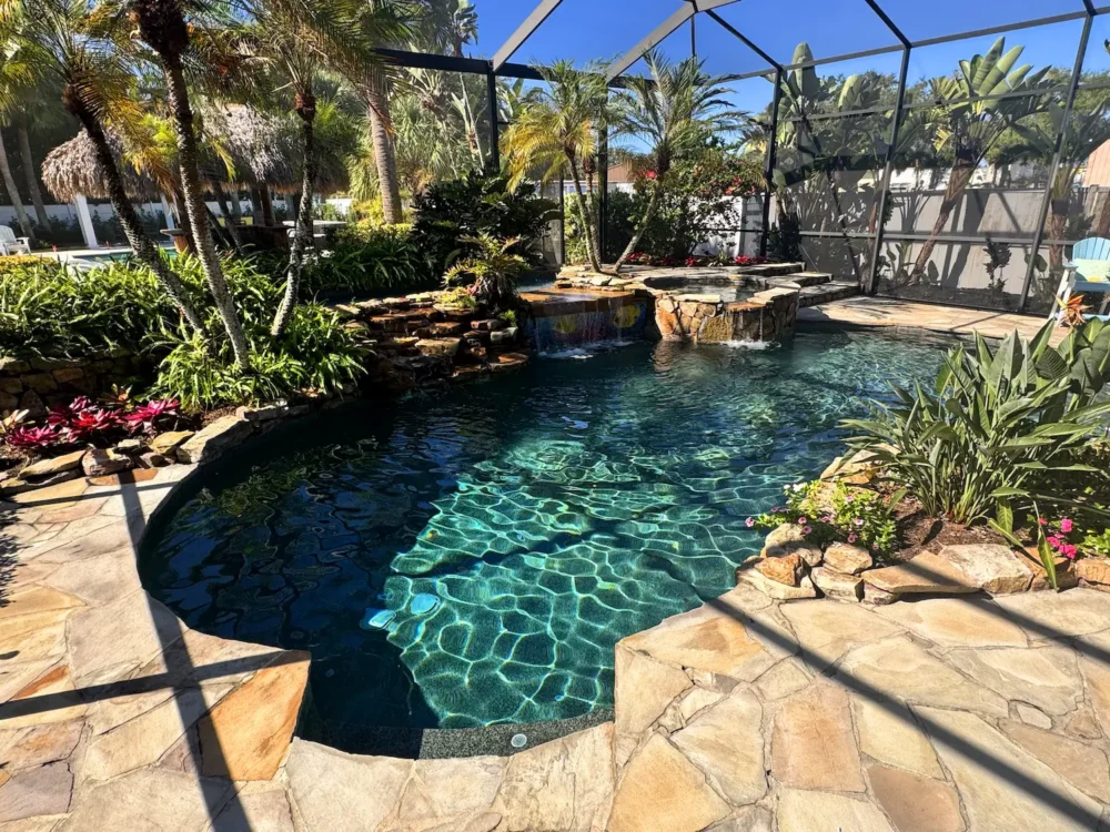 Freeform, lagoon style pool with spillover spa, waterfalls, and planters.