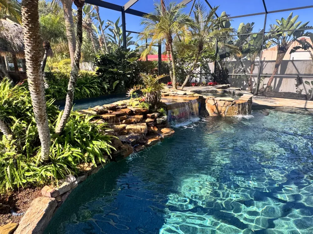 Freeform, lagoon style pool with spillover spa, waterfalls, and planters.