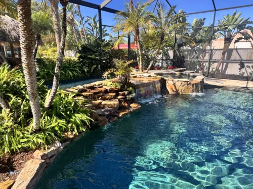 Freeform, lagoon style pool with spillover spa, waterfalls, and planters.
