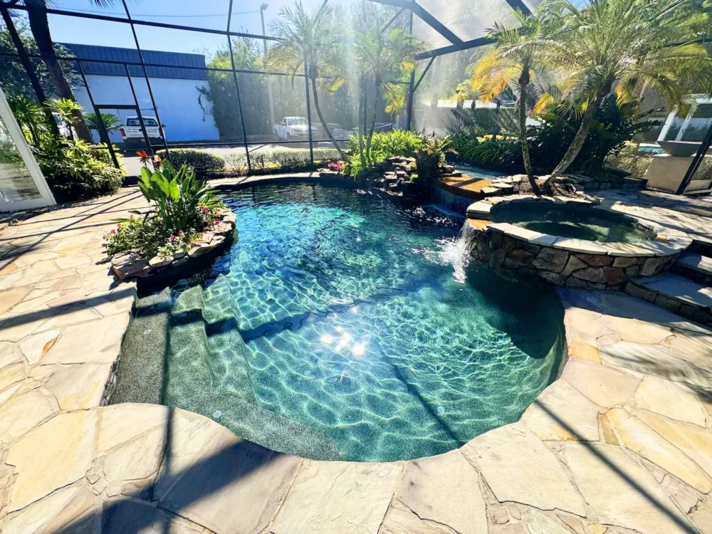 Freeform, lagoon style pool with spillover spa, waterfalls, and planters installed by a custom pool builder