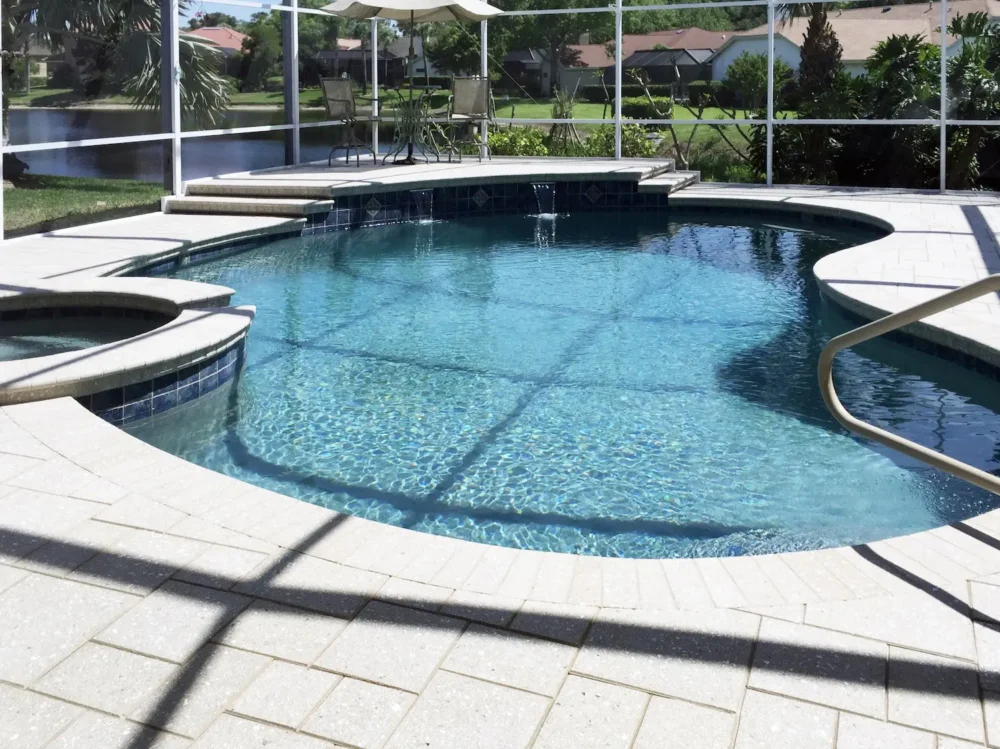 Freeform pool with spa and water features inside screen enclosure
