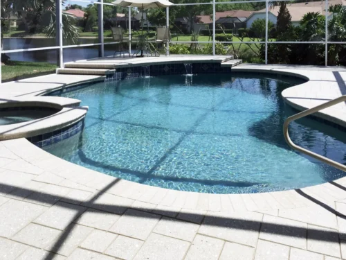 Freeform pool with spa and water features inside screen enclosure