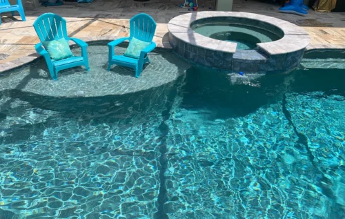 Freeform pool with sun shelf and spillover spa