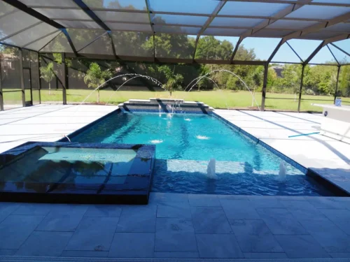 Geometric pool & spa with water & fire features inside screen enclosure.
