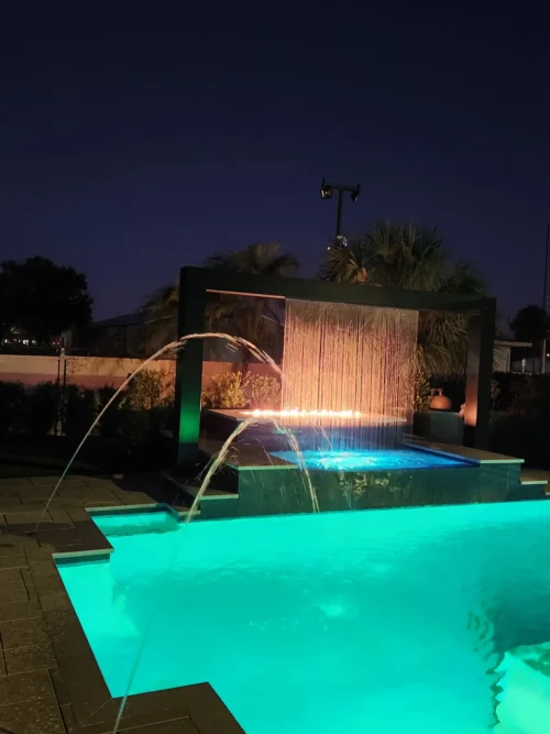 Geometric pool with LED lighting, water, and fire features at night
