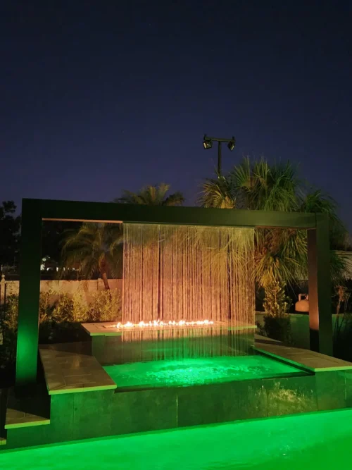 Geometric pool with LED lighting, water, and fire features at night