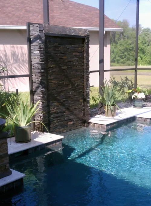 Geometric pool with contemporary vertical water wall with stacked stone and continuous sheer waterfall