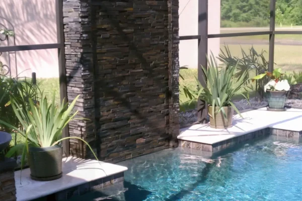 Geometric pool with contemporary vertical water wall with stacked stone and continuous sheer waterfall