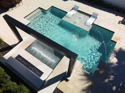 Geometric pool with integrated fire & water features and a sun shelf (tanning ledge).