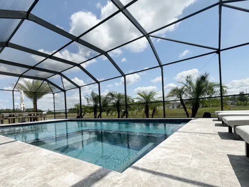 Geometric pool with spa inside screen enclosure.