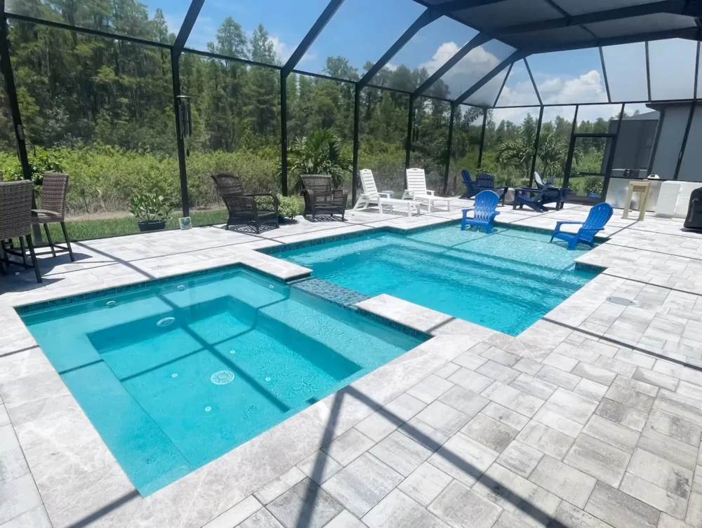 Geometric pool with spa & sun shelf inside screen enclosure.