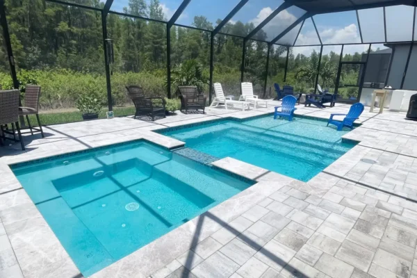 Geometric pool with spa & sun shelf inside screen enclosure.