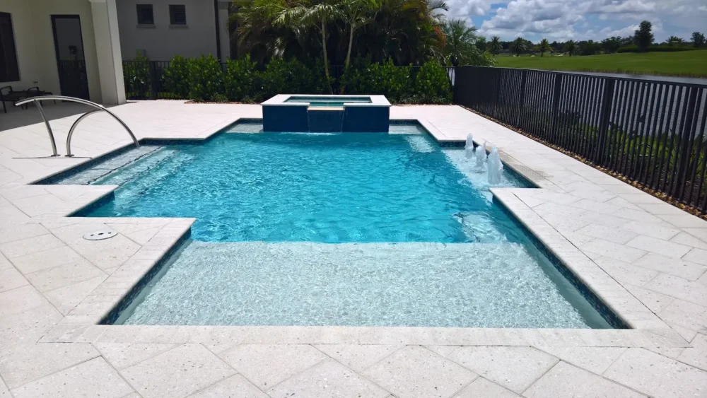 Geometric pool with spillover spa, bubblers, & sun shelf.