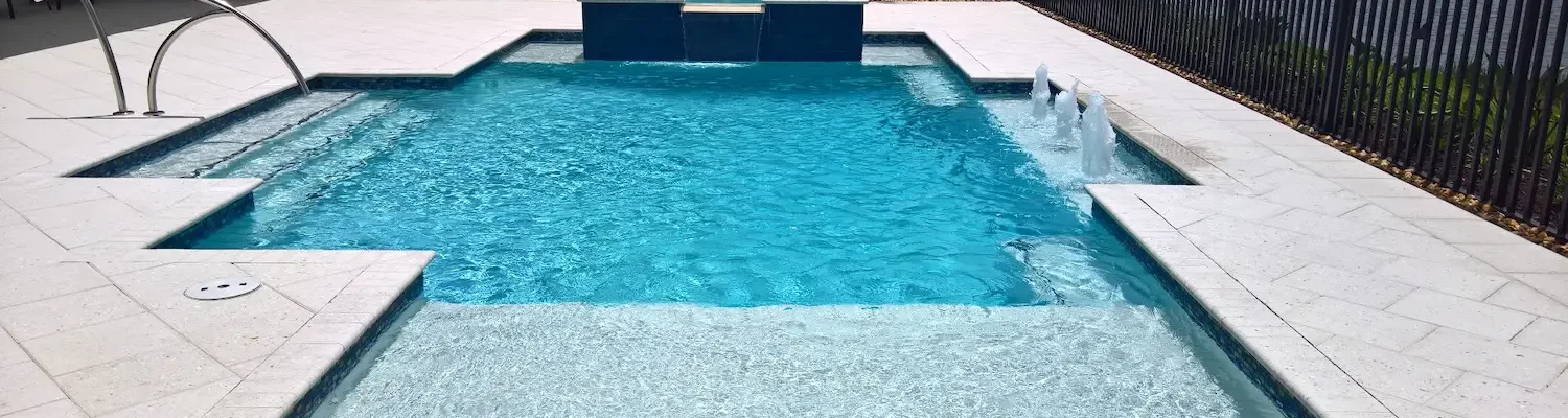 Geometric pool with spillover spa, bubblers, & sun shelf.