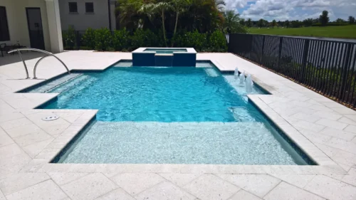 Geometric pool with spillover spa, bubblers, & sun shelf.