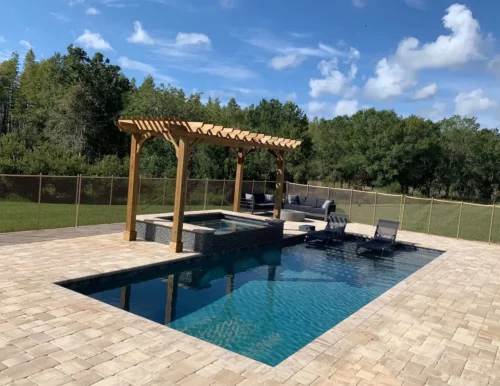 Geometric pool with spillover spa, sun shelf, pergola, & fire pit.