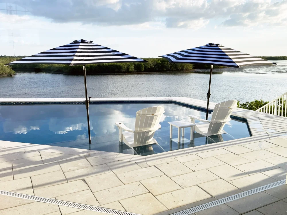 Geometric pool with sun shelf overlooking a lake from a custom pool builder