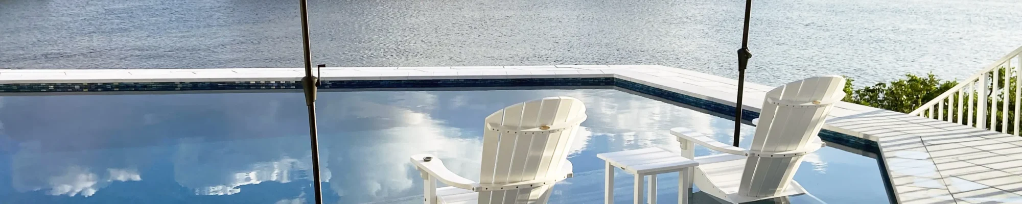 Geometric pool with sun shelf overlooking a lake from a custom pool builder