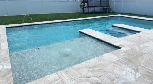 Geometric pool with sun shelf, spa, & water features.