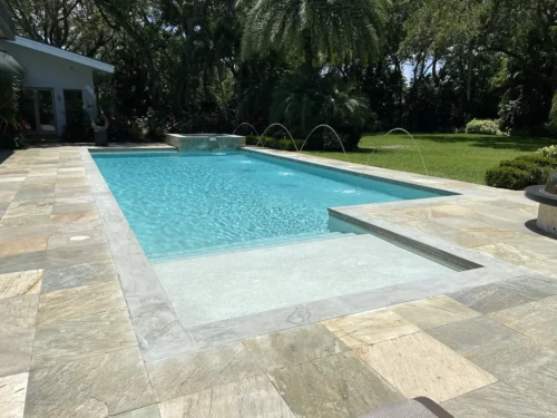 Geometric pool with sun shelf, spillover spa, & water features.